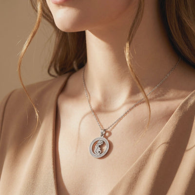 Silver pregnancy silhouette pendant necklace with a crystal halo, shown worn around a woman's neck.