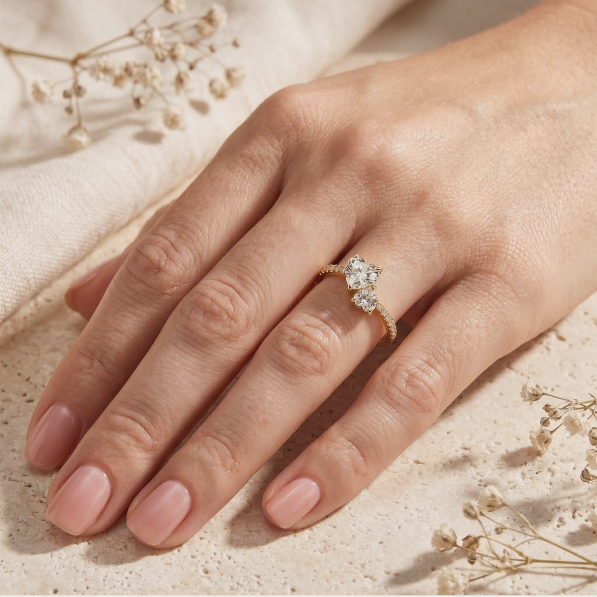 Yellow-gold-finish Toi et Moi ring with two heart-cut clear stones and pavé accents, worn on a hand.