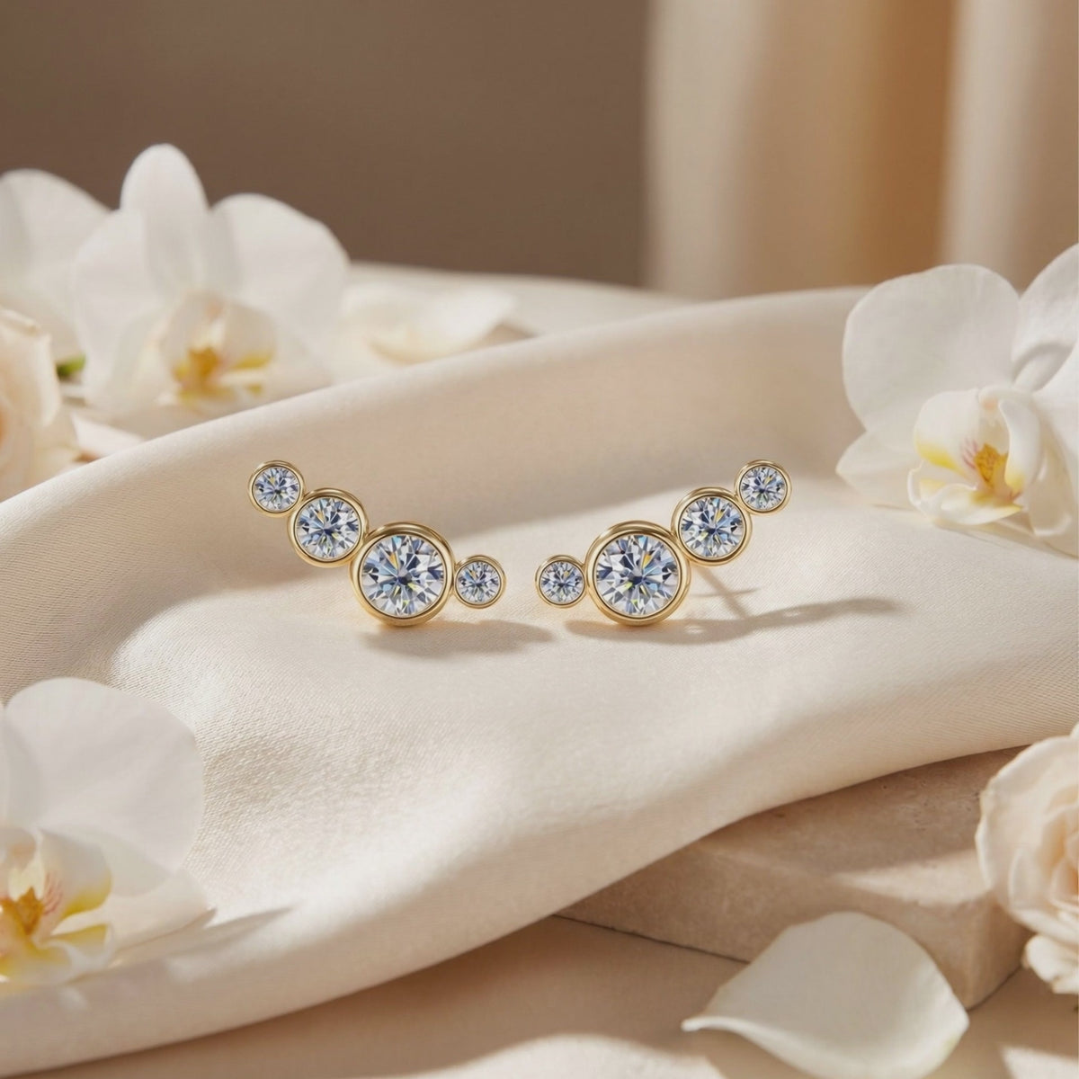 Pair of gold-toned moissanite ear climbers on cream fabric surrounded by white orchids.