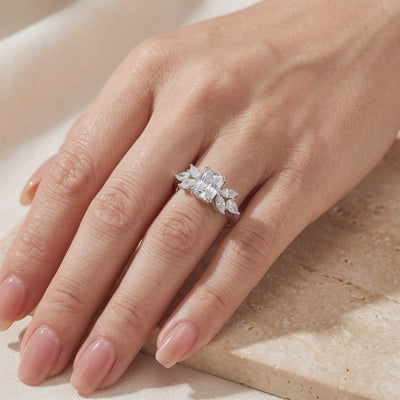 Close-up video of the silver ring with a radiant-cut clear center stone and marquise accents worn on a hand.