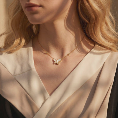 Gold-tone necklace with a mother-of-pearl butterfly pendant, shown worn at the neck