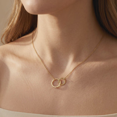 Gold-tone necklace with textured interlocking circles worn on the upper chest