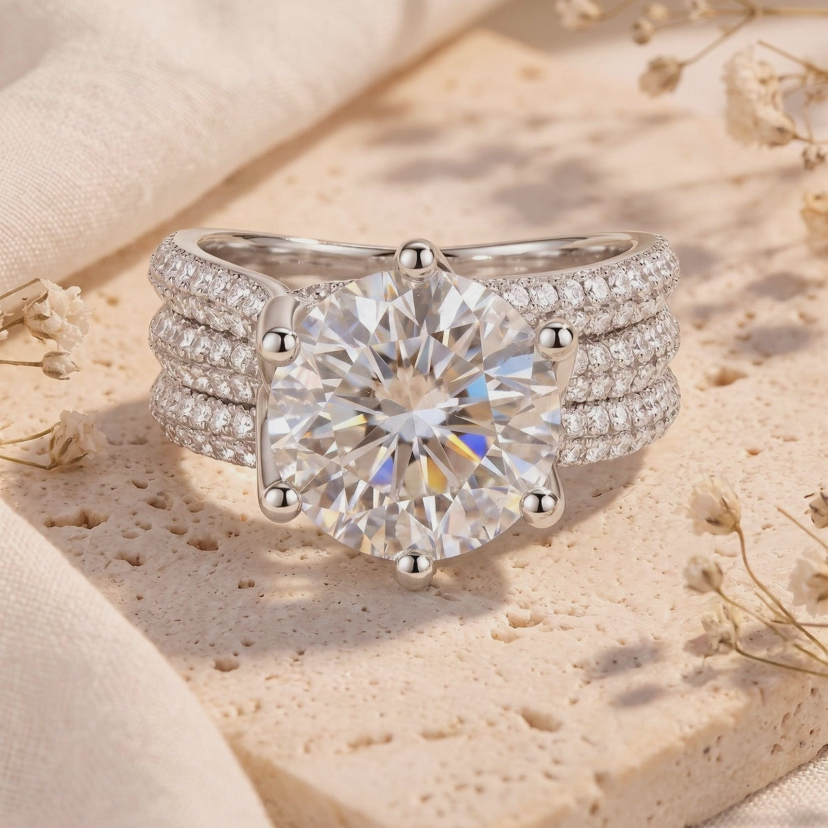 Silver ring with a large round faceted center stone and three-row pavé band displayed on a textured stone block.