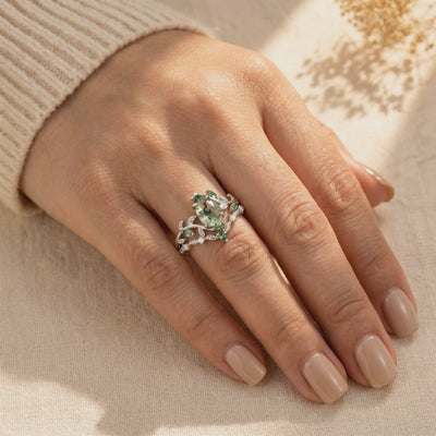 Pear-cut moss agate silver vine ring set worn on a hand beside a ribbed sleeve.