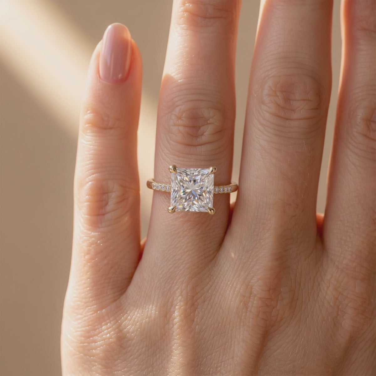 Princess-cut solitaire ring with a pavé band worn on a hand.