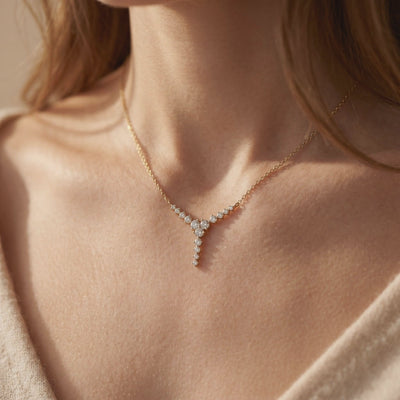 Gold-tone Y-drop moissanite necklace displayed on a model’s collarbone over a beige sweater.