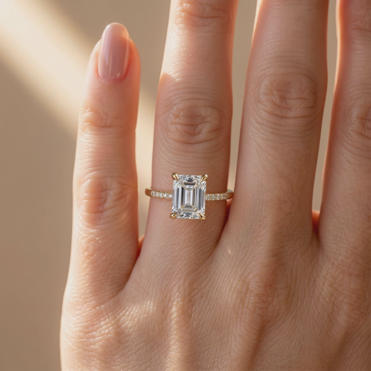 Emerald-cut pavé solitaire ring with a clear rectangular center stone, shown worn on a hand in a front view.