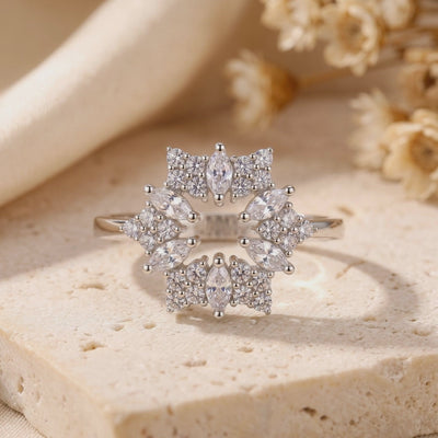 Close-up of the silver starburst ring standing upright on a beige stone surface.
