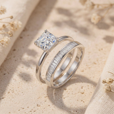 Close-up of a silver ring set displayed upright on a textured surface with dried floral accents.
