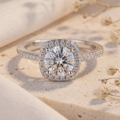Close-up front view of a silver halo ring with a round center stone, cushion pavé halo, and gem-set band on stone.
