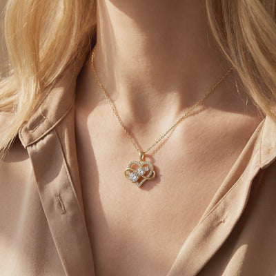 Gold-tone heart and infinity moissanite pendant necklace worn around a woman's neck.