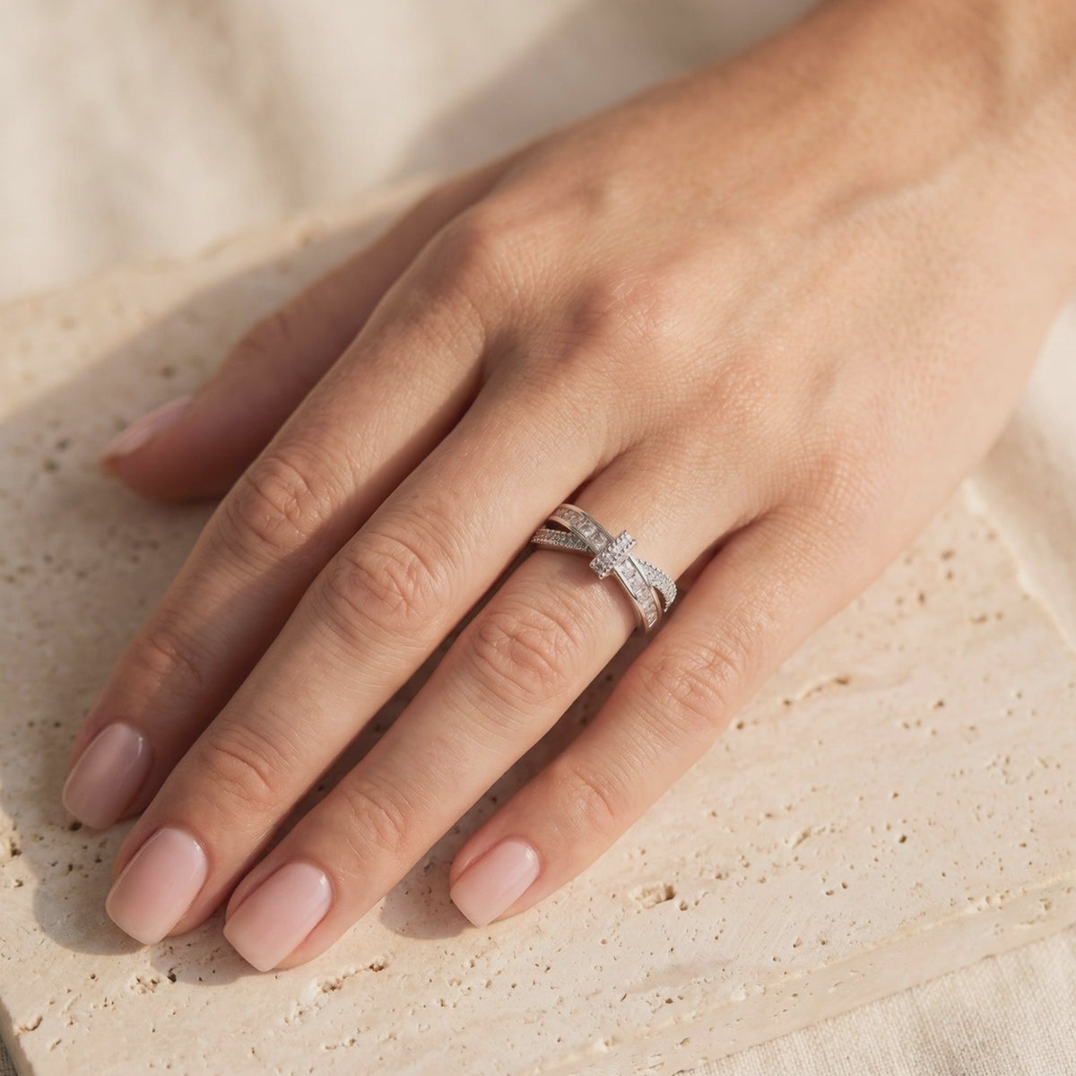 Video preview of a silver criss-cross ribbon ring with CZ accents worn on a hand.