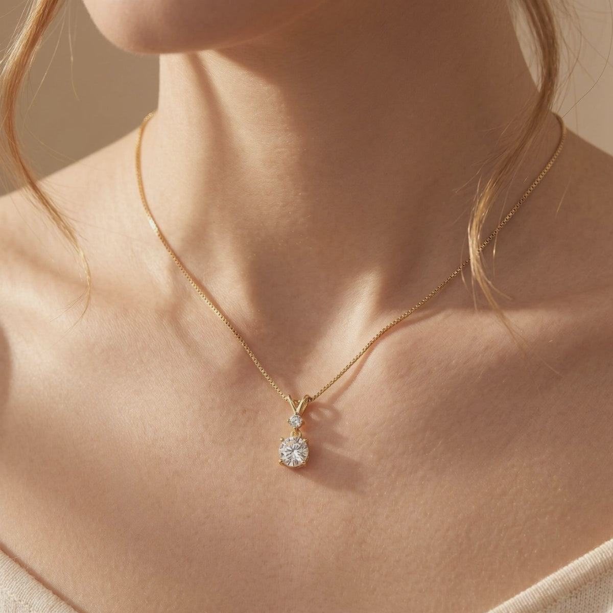 Woman wearing a gold-tone pendant necklace with two stacked round moissanite stones on a delicate chain.