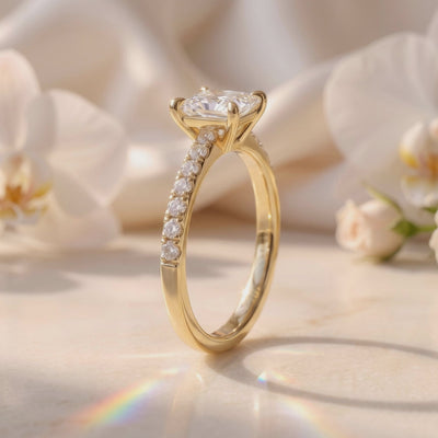 Side profile of a gold-tone princess-cut solitaire ring showing its prong setting and pavé band.
