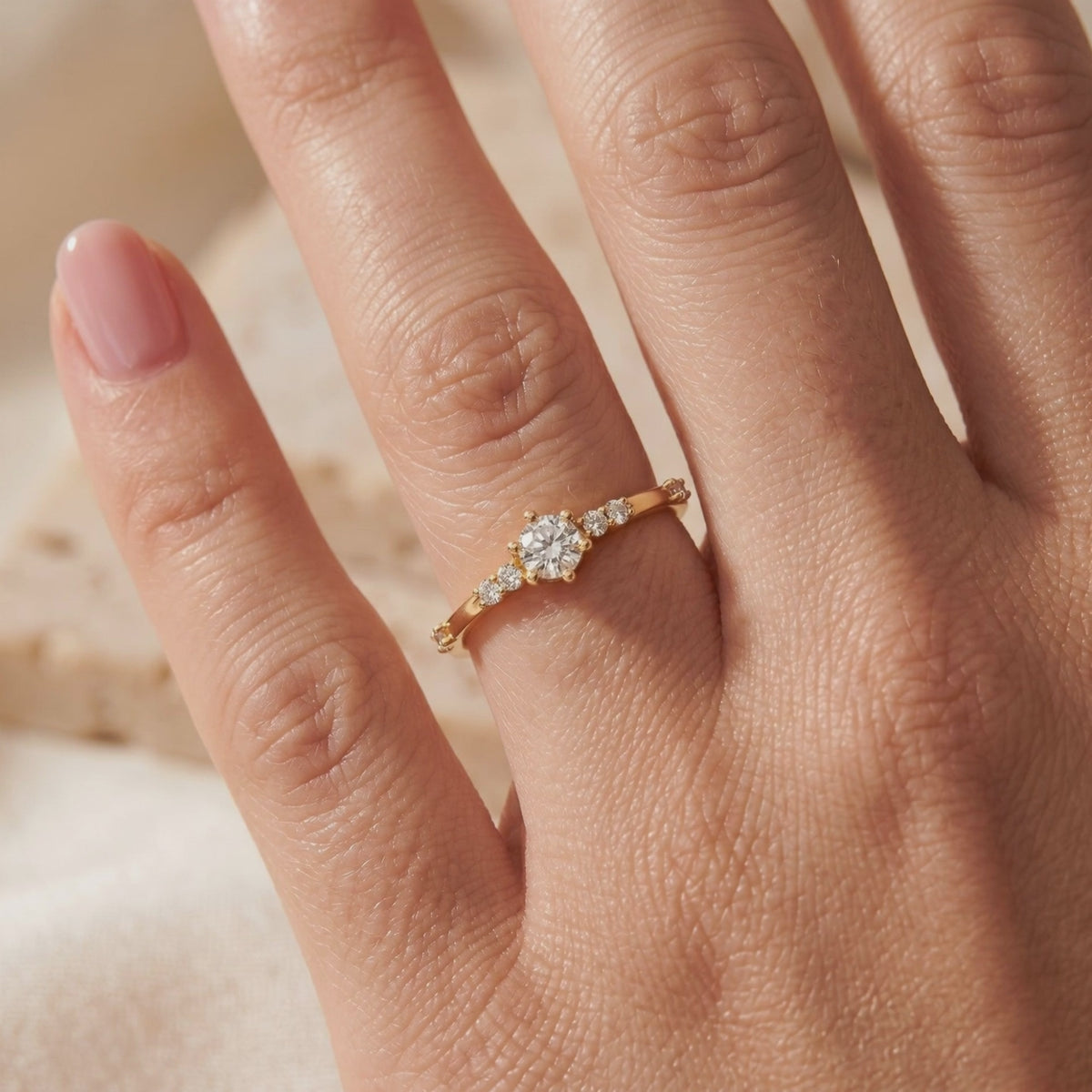 Yellow gold-tone round moissanite ring with side accent stones worn on a finger.