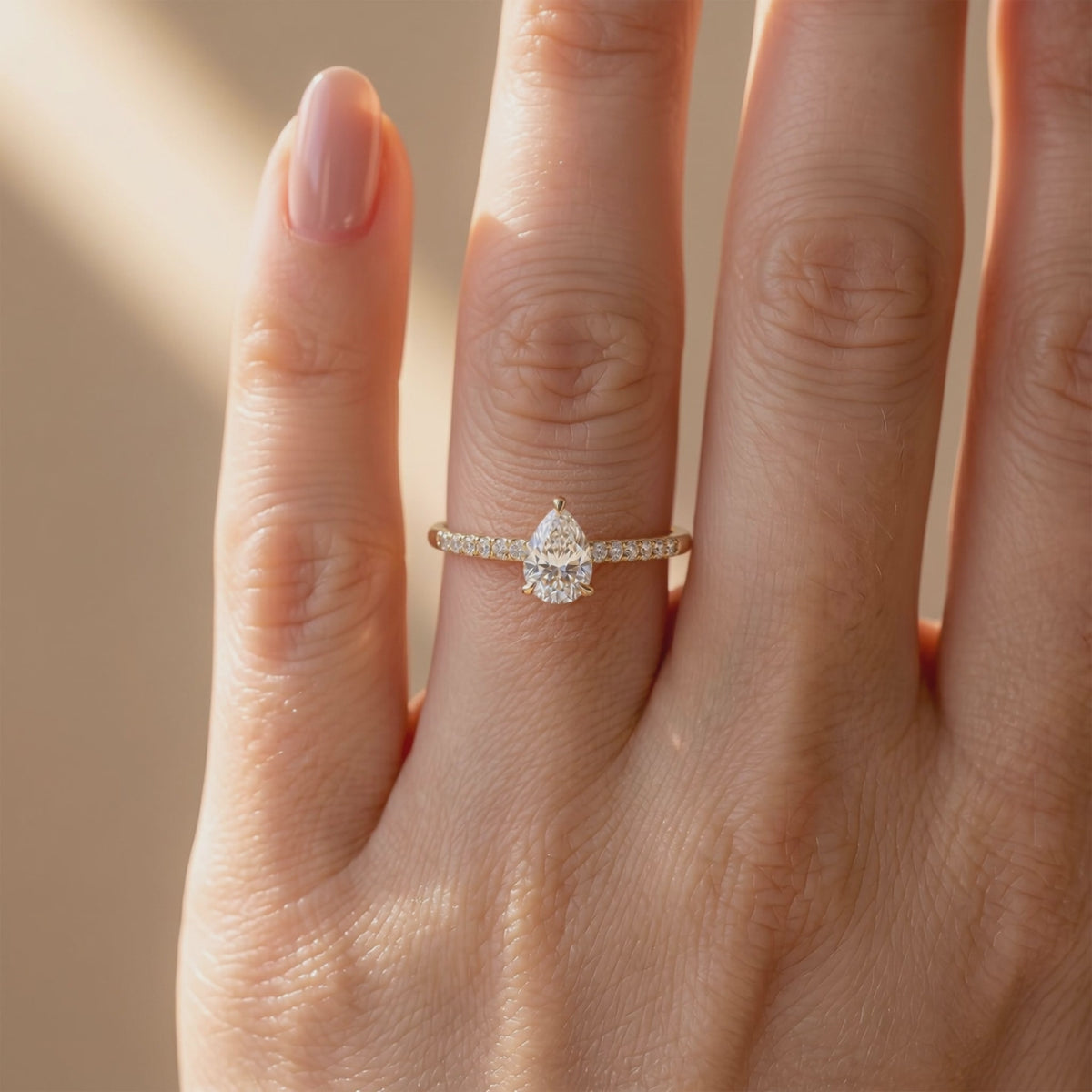 Pear-cut pavé solitaire ring worn on a finger in a close front view.
