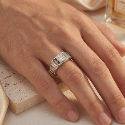 Silver ring with a princess-cut simulated diamond worn on a hand over travertine and silk fabric.