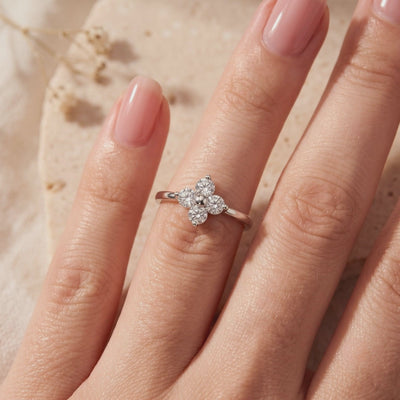 Silver clover ring worn on a hand, featuring four round clear cubic zirconia stones in a floral cluster.