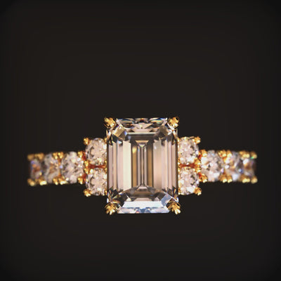 A solid gold ring with an emerald-cut moissanite center stone.