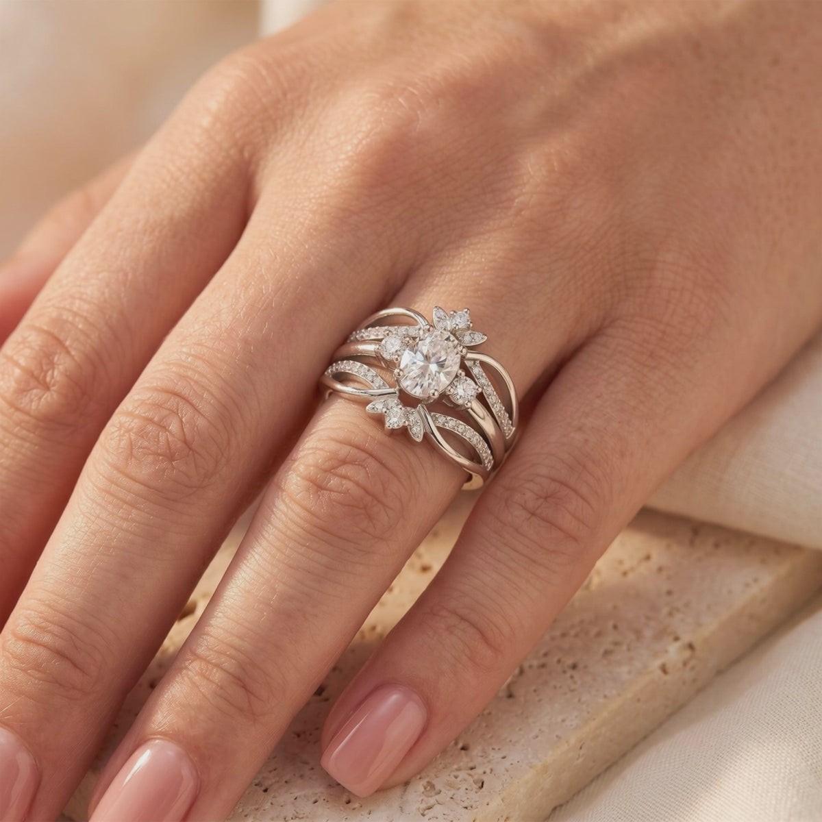 Sterling silver ring with an oval center stone and layered pavé bands, shown worn on a finger.