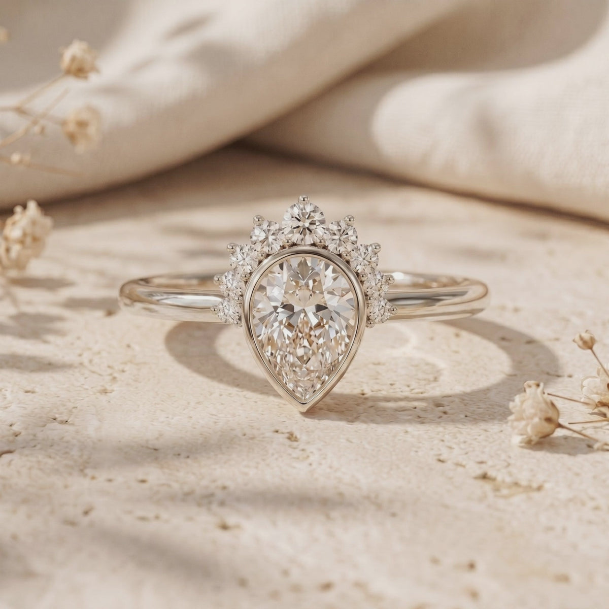 Silver-tone Amaraea ring with a pear-cut moissanite and tiara halo, displayed upright on a textured surface.