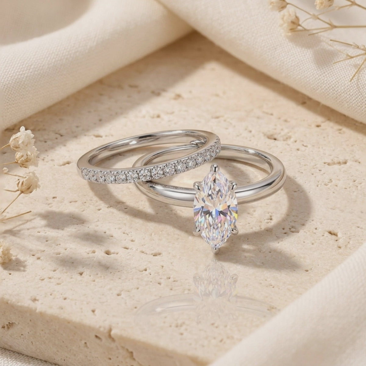 Silver marquise-cut ring set with a pavé band arranged on a textured stone surface