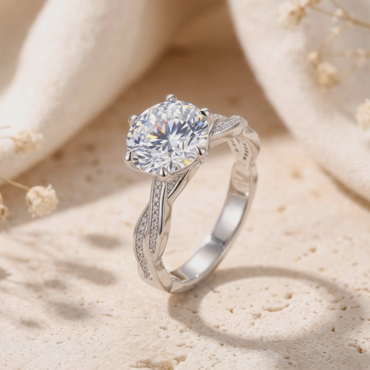 Close-up of a silver ring with a round clear center stone and twisted pavé band standing on a textured surface.