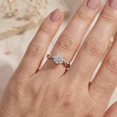 Round moissanite ring with a silver-toned twisted vine band, worn on a hand.