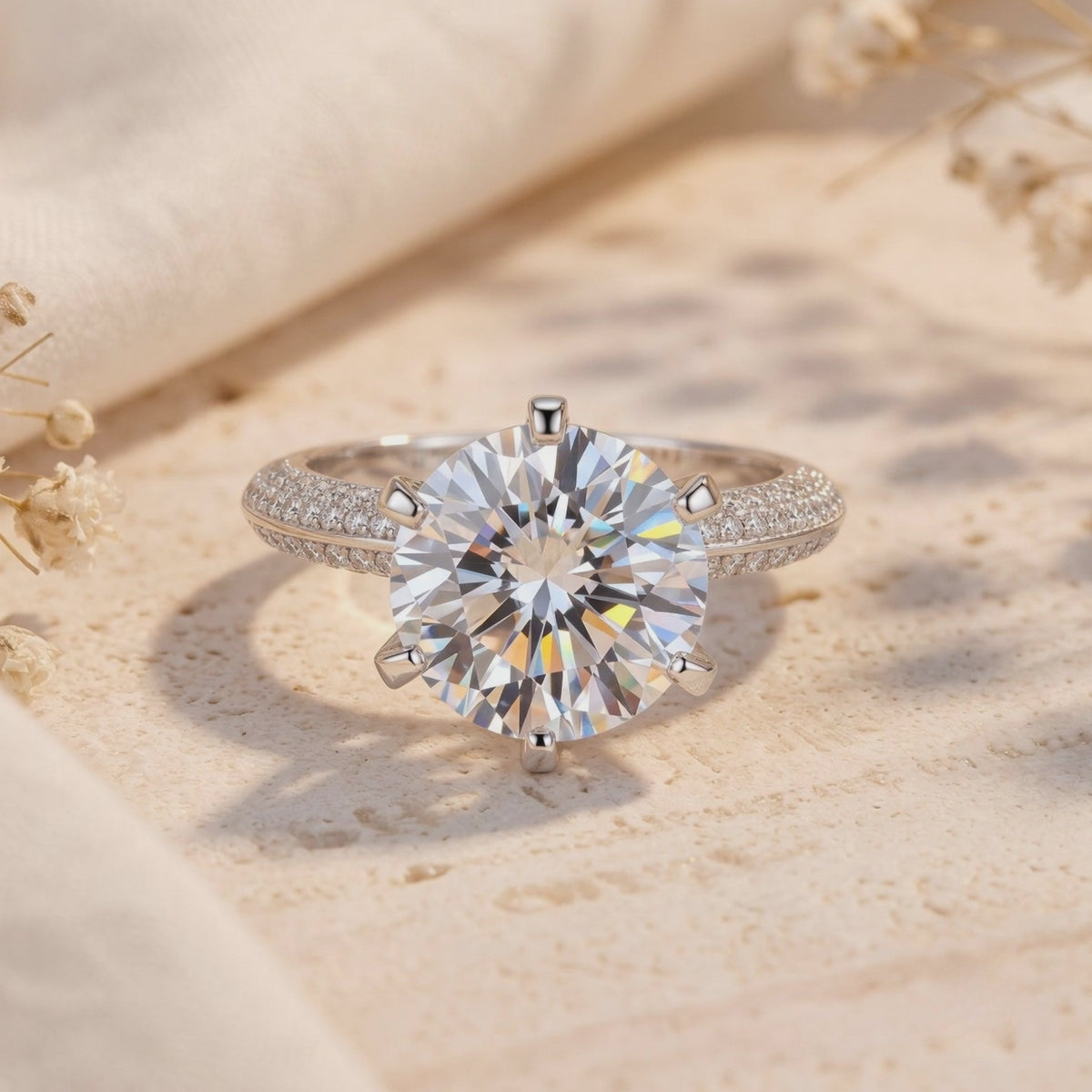 Silver solitaire ring with a large round stone and micro-pavé band resting on a textured surface.