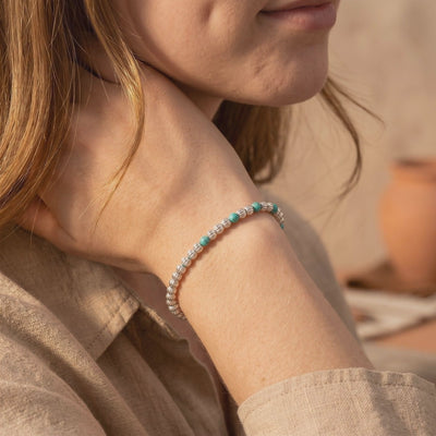 Model wearing the Pecos turquoise bracelet with ribbed silver beads and teal turquoise accents on her wrist.