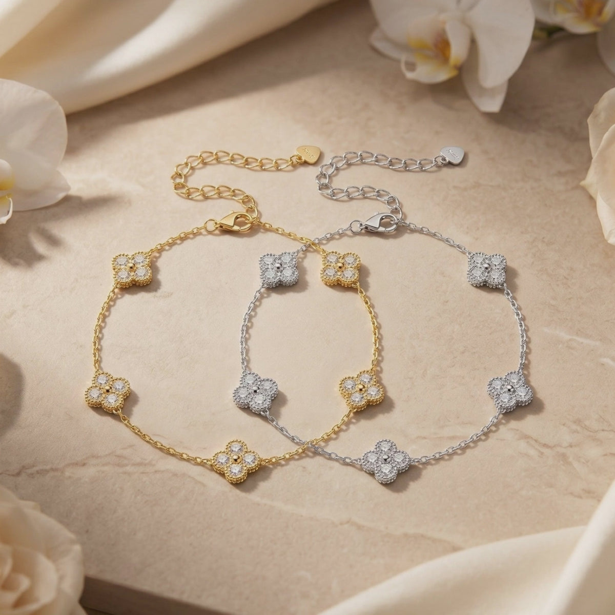 Gold and silver moissanite clover bracelets displayed flat with extender chains on a stone surface.