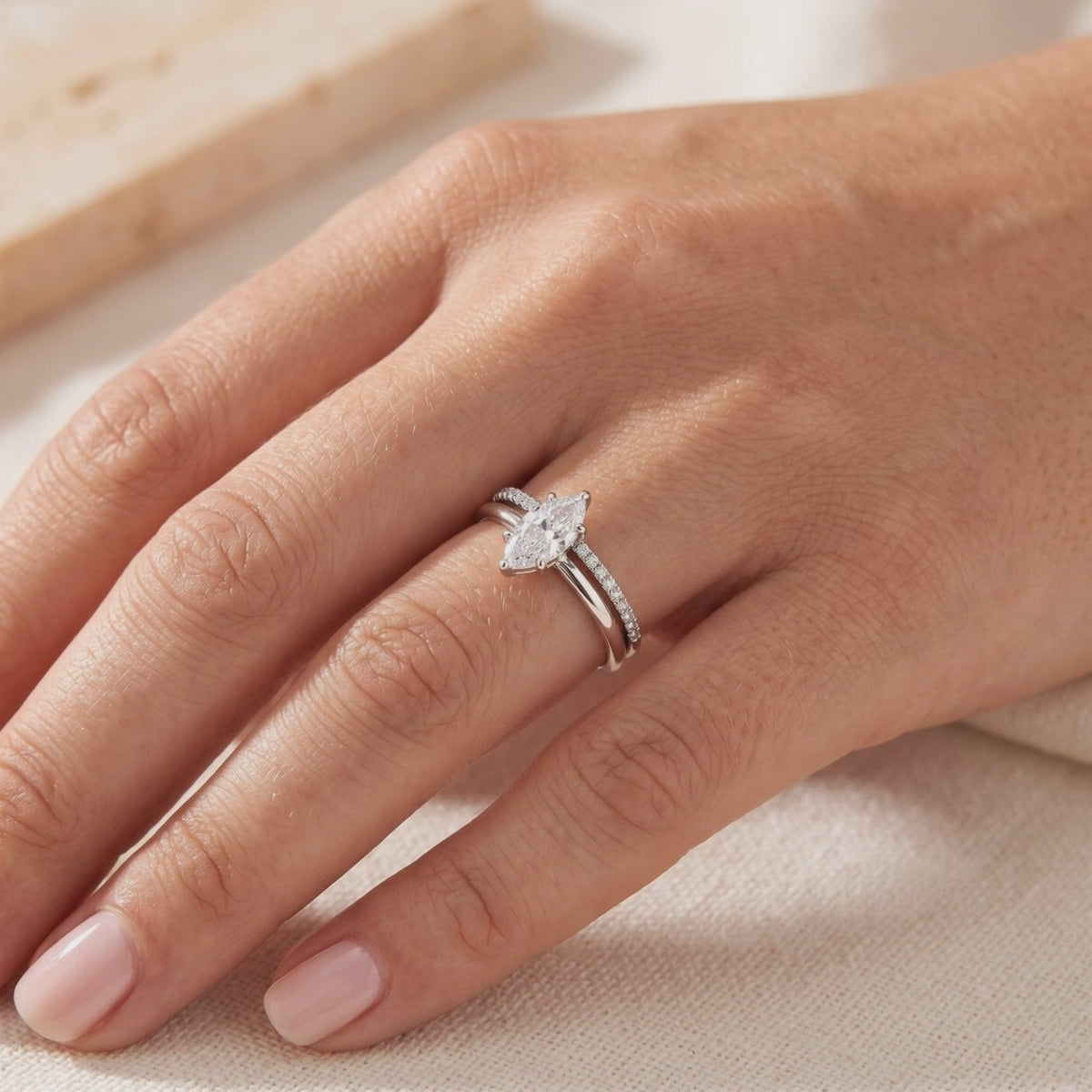Silver marquise-cut ring set with a pavé band worn on a hand
