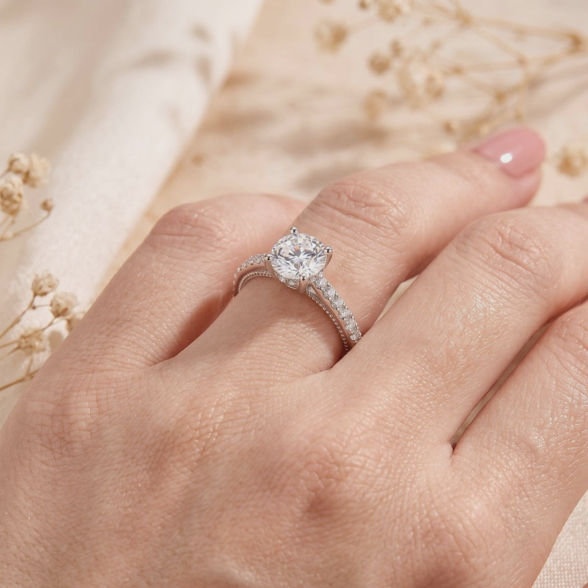 Silver ring with a round clear center stone and pavé accent band, worn on a finger.