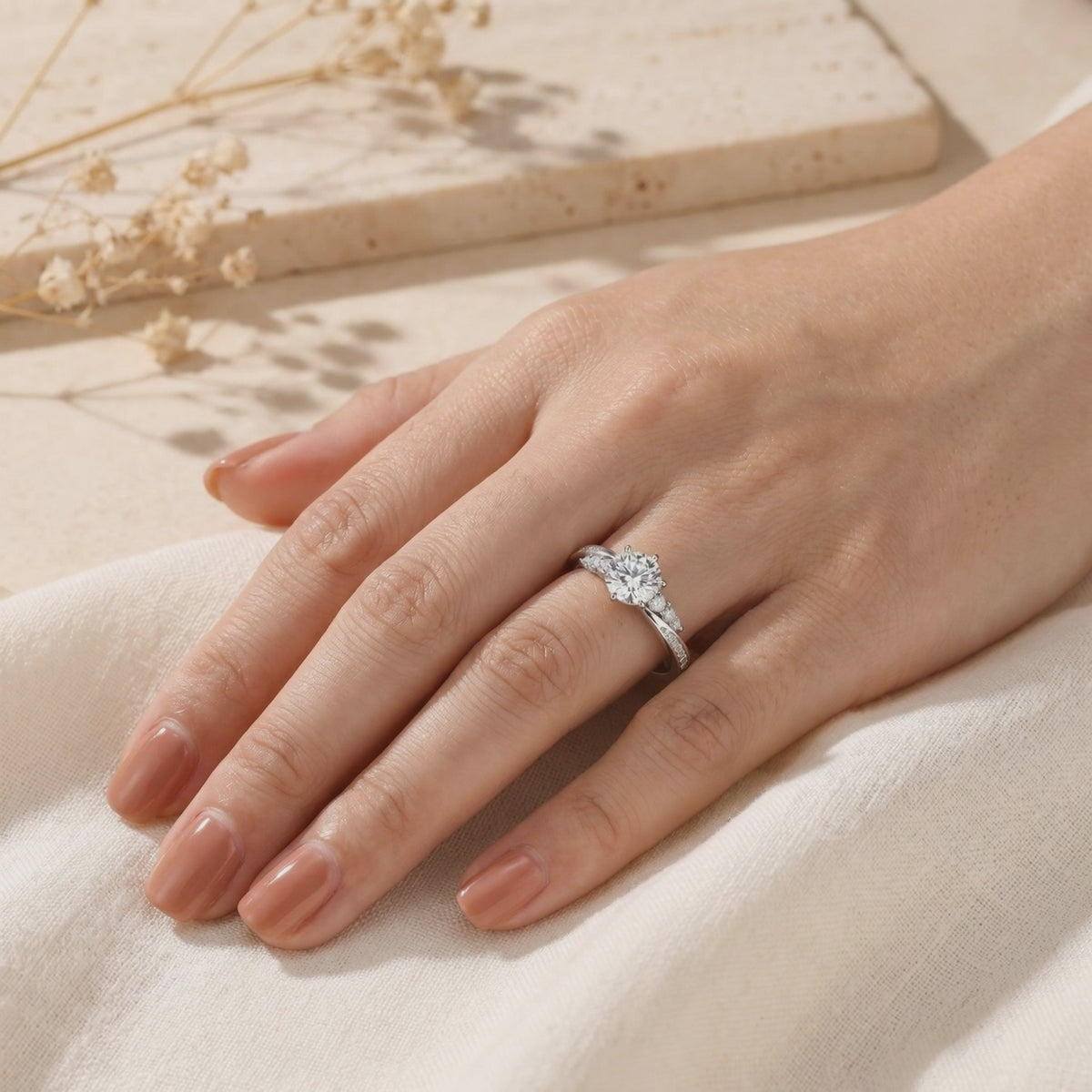 The moissanite ring with a round center stone and twisted pavé band shown worn on a hand.