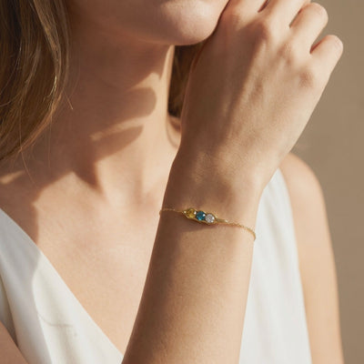 Gold-tone pea pod bracelet with yellow, blue, and clear gems shown on a model's wrist.