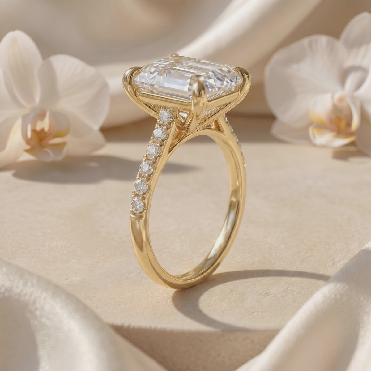 Side view of a yellow-gold-tone solitaire ring showing the emerald-cut moissanite setting and pavé-accented band.