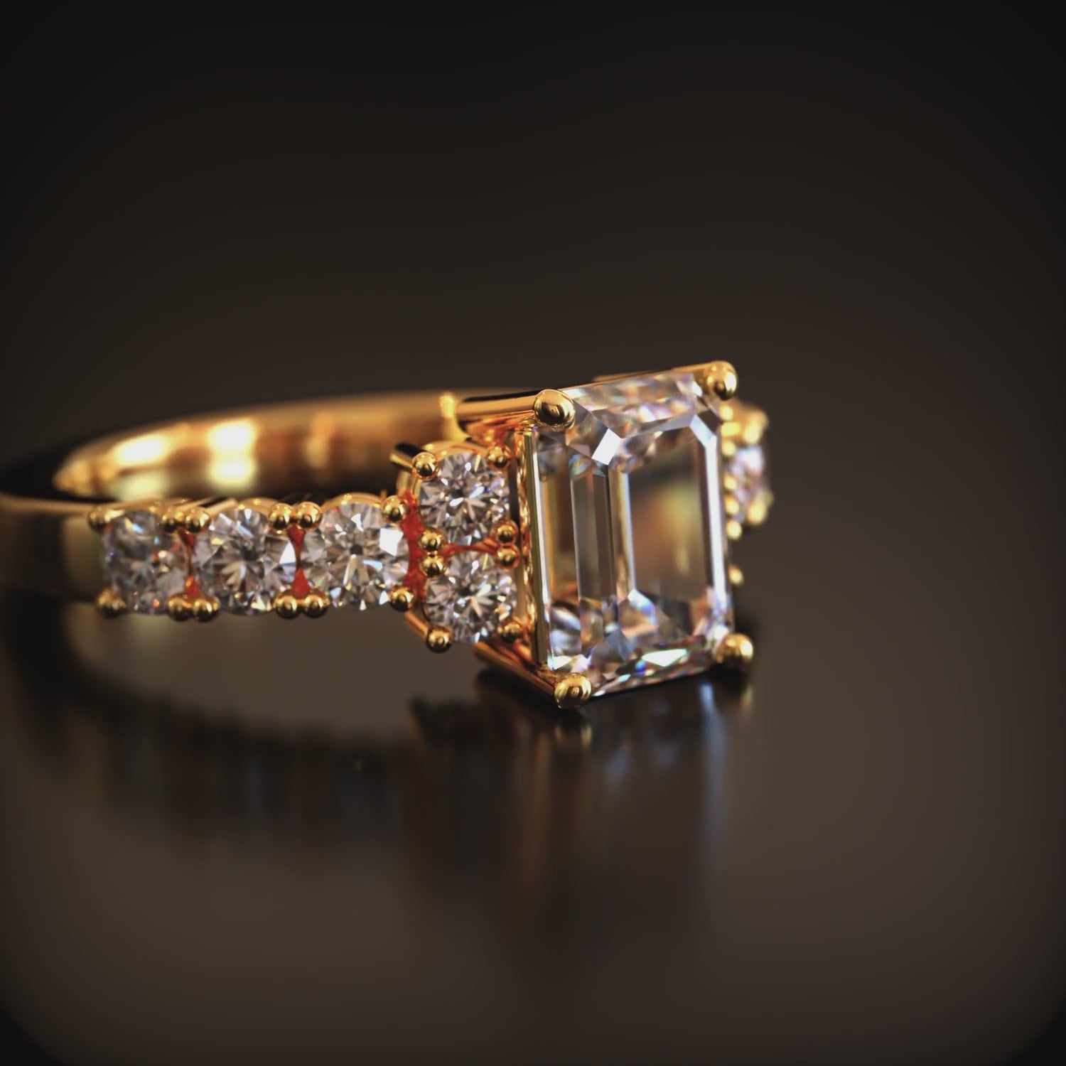 A solid gold ring with an emerald-cut moissanite center stone.