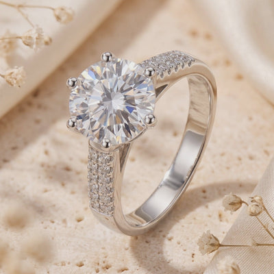 Close-up of an upright sterling silver six-prong ring with a large round center stone and pavé-set shoulders.