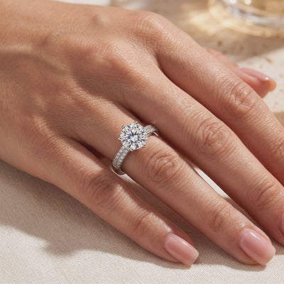 Sterling silver six-prong ring with a round center stone and pavé-set shoulders, worn on a hand.