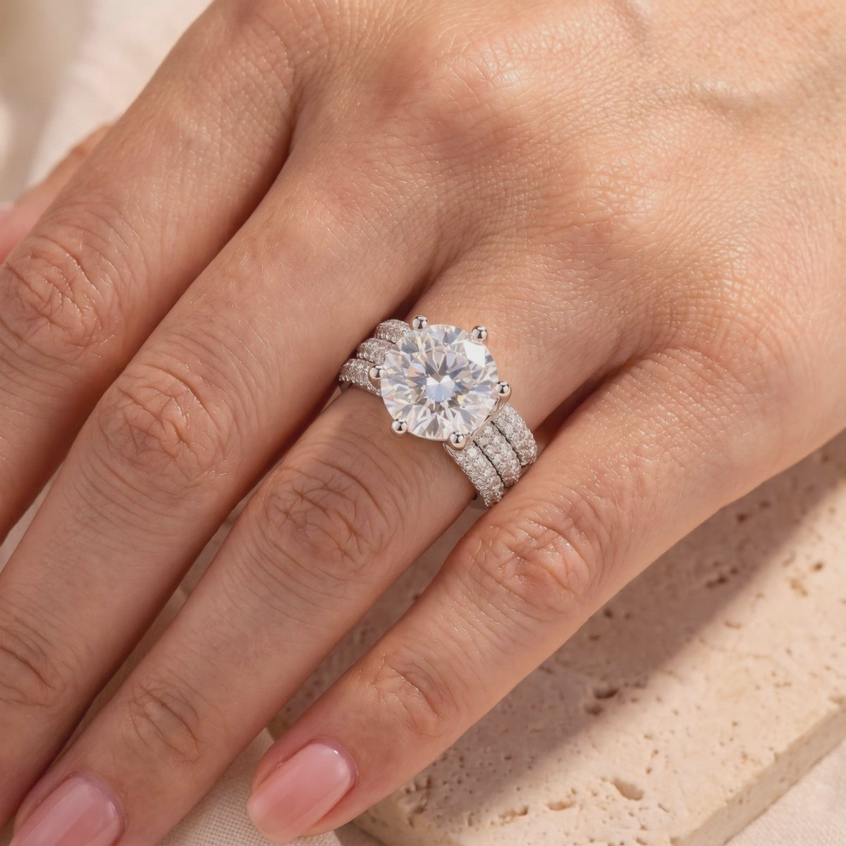 Silver ring with a large round clear center stone and three-row pavé band worn on a hand.