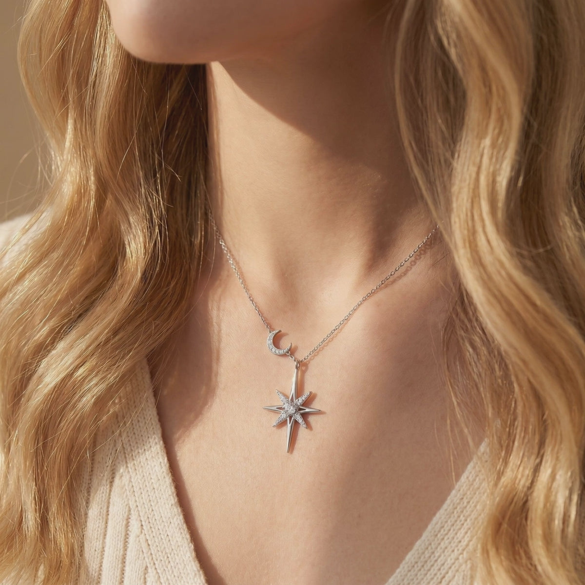 Close-up of a model wearing a silver-tone starburst and crescent moon pendant necklace.