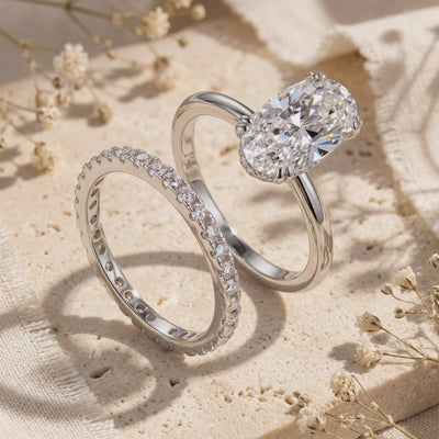 Silver oval solitaire ring and pavé eternity band displayed upright on a textured stone surface.