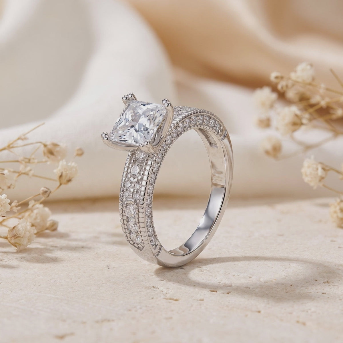 Three-quarter view of a silver ring standing upright, showing its raised square-cut setting and pavé band.