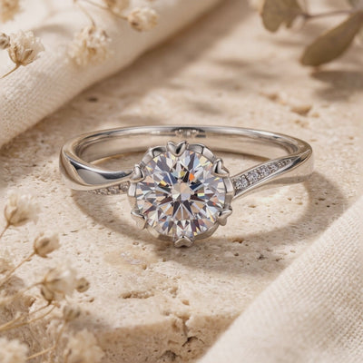 Close-up of the silver Liorabelle ring with a round clear stone, heart-shaped prongs, and accent stones on the band.
