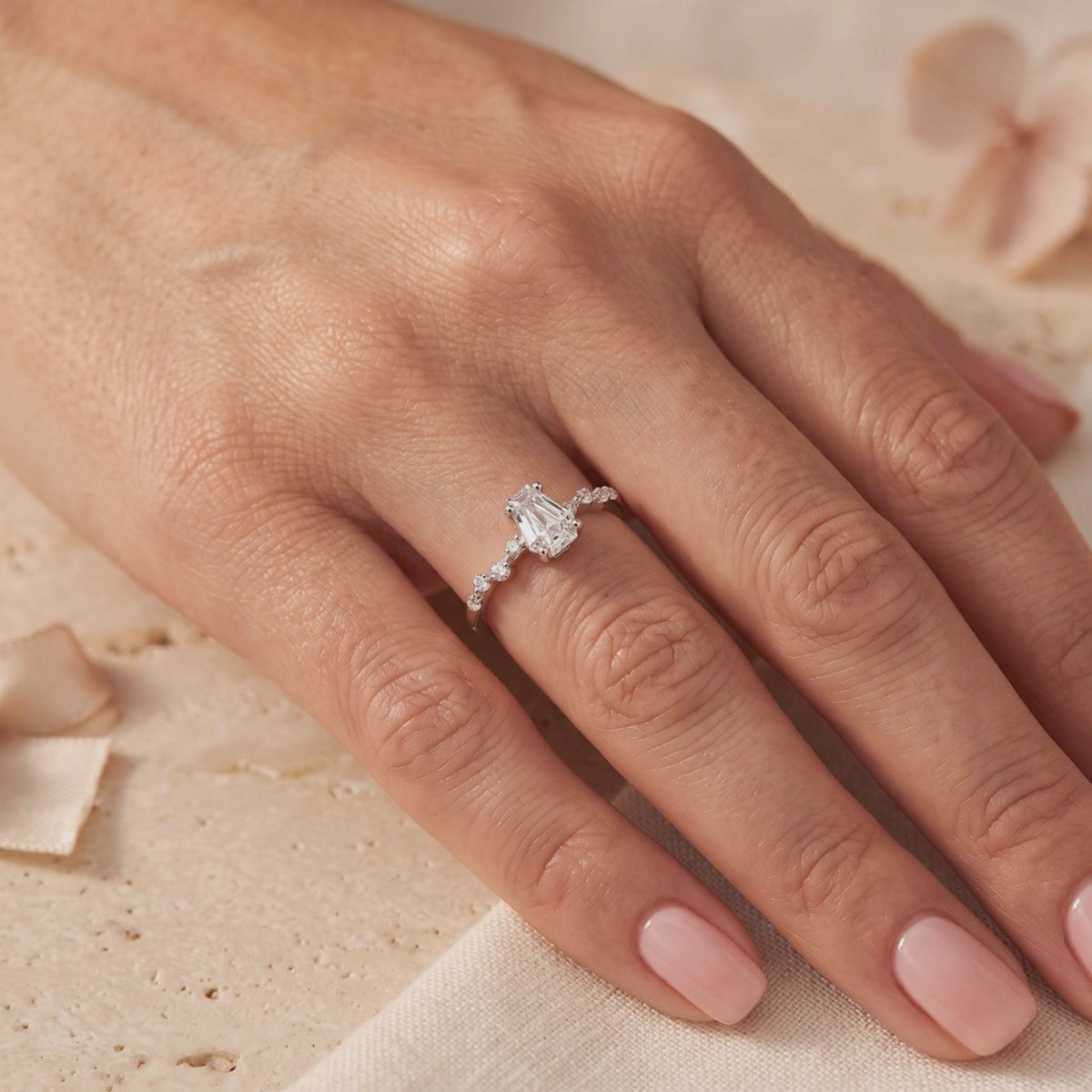 Silver ring with a coffin-cut clear center stone and small side stones, worn on a finger.