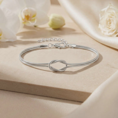 Silver double snake-chain knot bracelet displayed flat with lobster clasp and extender chain visible.